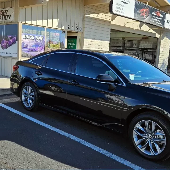 Black 2022 Toyota Avalon with freshly tinted windows, beside the King Auto Tint sign on Fulton Ave, Sacramento