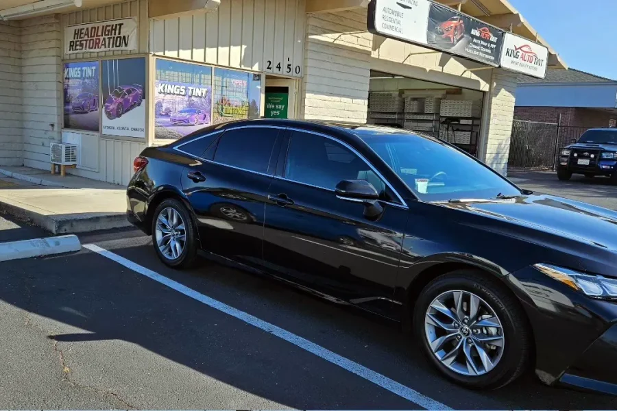 Black 2022 Toyota Avalon with freshly tinted windows, beside the King Auto Tint sign on Fulton Ave, Sacramento