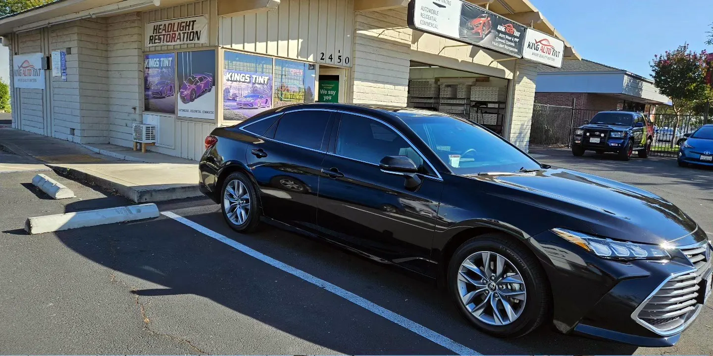 Black 2022 Toyota Avalon with freshly tinted windows, beside the King Auto Tint sign on Fulton Ave, Sacramento