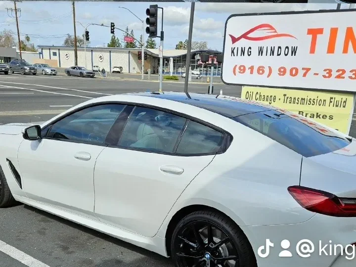 White 2024 BMW 840i Gran Coupe with freshly tinted windows, outside the King Window Tint shop on Fulton Ave in Sacramento
