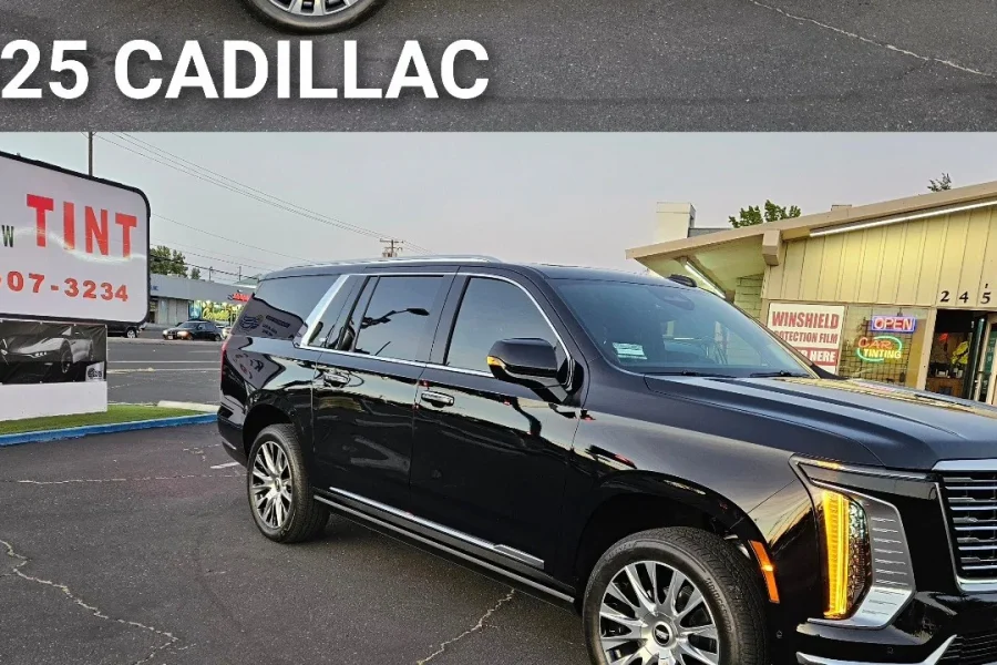 Black 2025 Cadillac Escalade ESV with freshly tinted windows, beside the King Window Tint sign on Fulton Ave, Sacramento