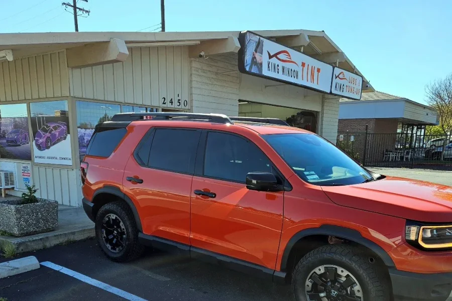 Orange 2026 Honda Passport with freshly tinted windows, in the King Window Tint parking lot on Fulton Avenue, Sacramento