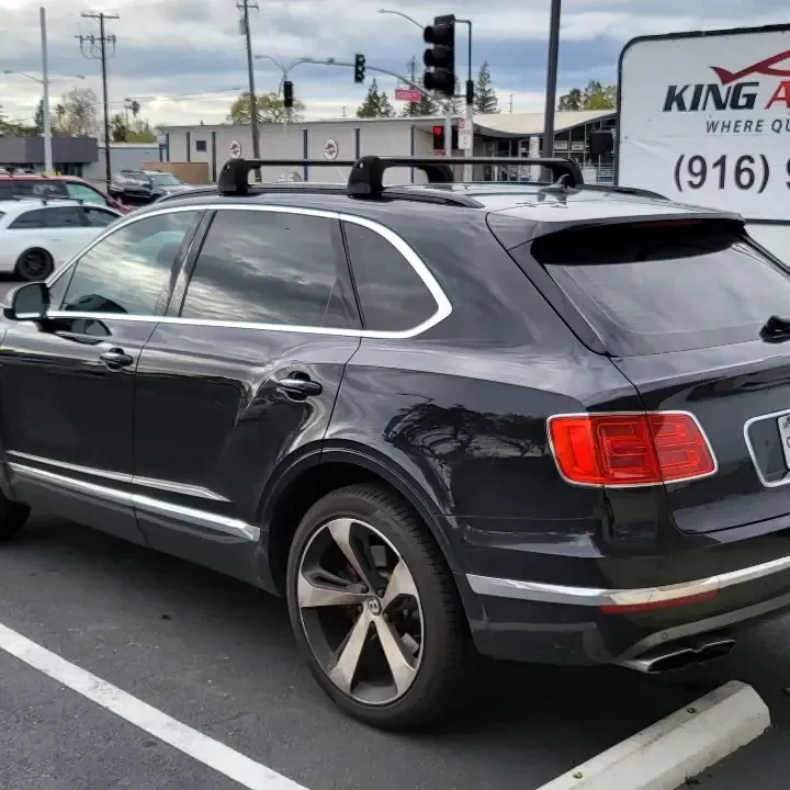 Black Bentley Bentayga with freshly tinted windows, beside the King Auto Tint sign on Fulton Ave, Sacramento
