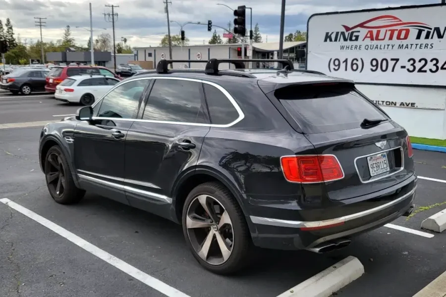 Black Bentley Bentayga with freshly tinted windows, beside the King Auto Tint sign on Fulton Ave, Sacramento