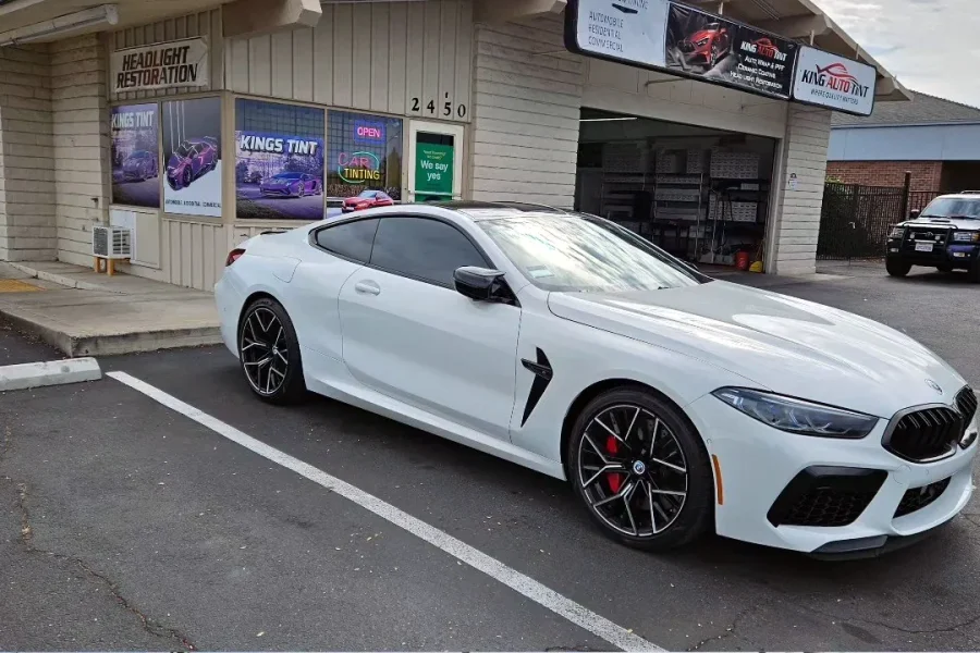 White BMW M8 with freshly tinted windows, parked in front of King Auto Tint at 2450 Fulton Ave, Sacramento