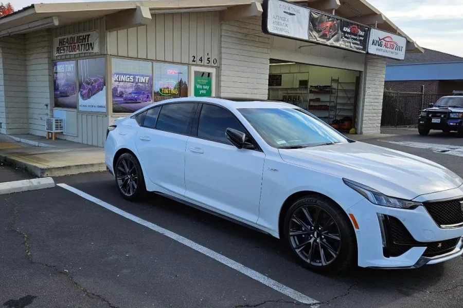 White Cadillac CT5 with freshly tinted windows, beside the King Auto Tint sign on Fulton Ave, Sacramento
