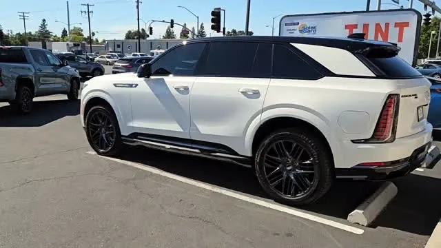White Cadillac electric SUV with freshly tinted windows, in the King Window Tint parking lot on Fulton Avenue, Sacramento
