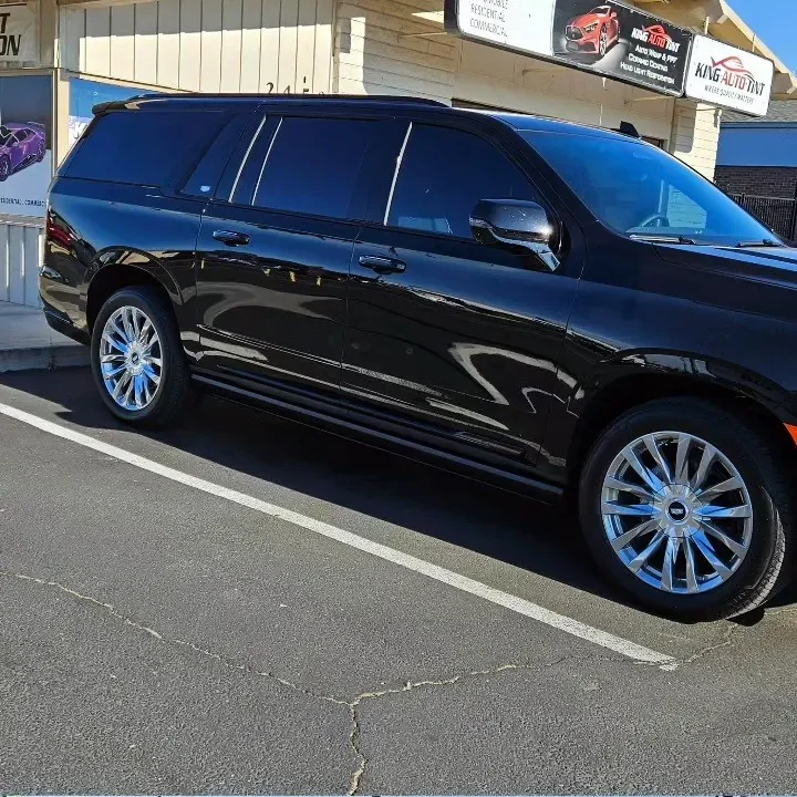 Black Cadillac Escalade ESV with freshly tinted windows, beside the King Auto Tint sign on Fulton Ave, Sacramento