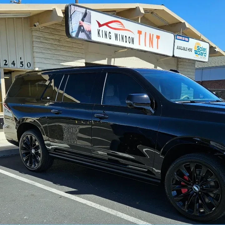 Black Cadillac Escalade with freshly tinted windows, in the King Window Tint parking lot on Fulton Avenue, Sacramento
