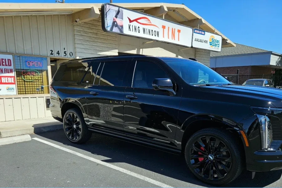 Black Cadillac Escalade with freshly tinted windows, in the King Window Tint parking lot on Fulton Avenue, Sacramento