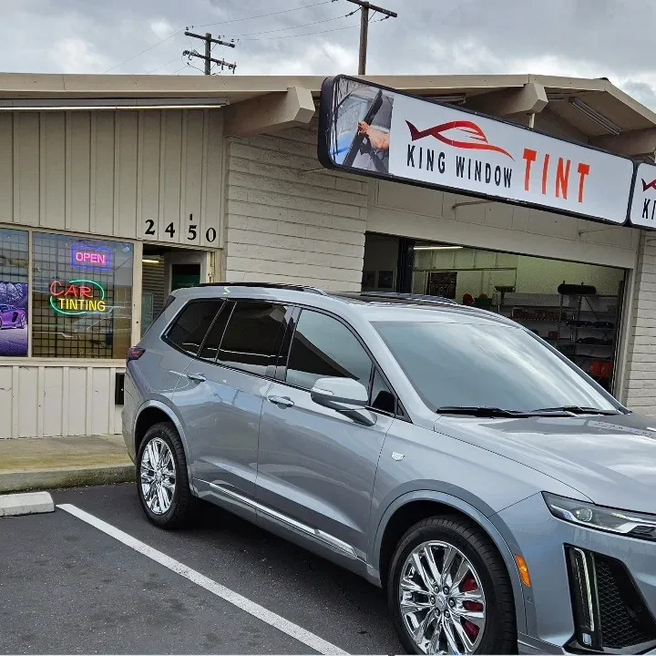 Gray Cadillac XT6 with freshly tinted windows, beside the King Window Tint sign on Fulton Ave, Sacramento