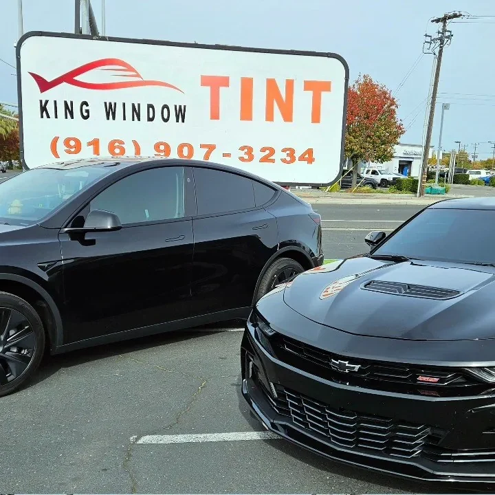 Black Chevrolet Camaro SS with freshly tinted windows, outside the King Window Tint shop on Fulton Ave in Sacramento (shown with a black Tesla Model Y)