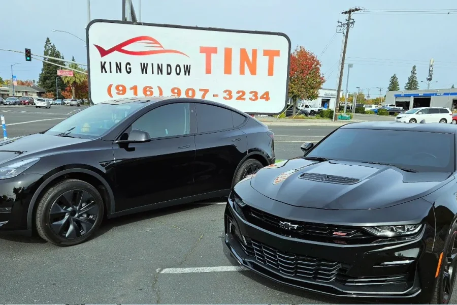 Black Chevrolet Camaro SS with freshly tinted windows, outside the King Window Tint shop on Fulton Ave in Sacramento (shown with a black Tesla Model Y)