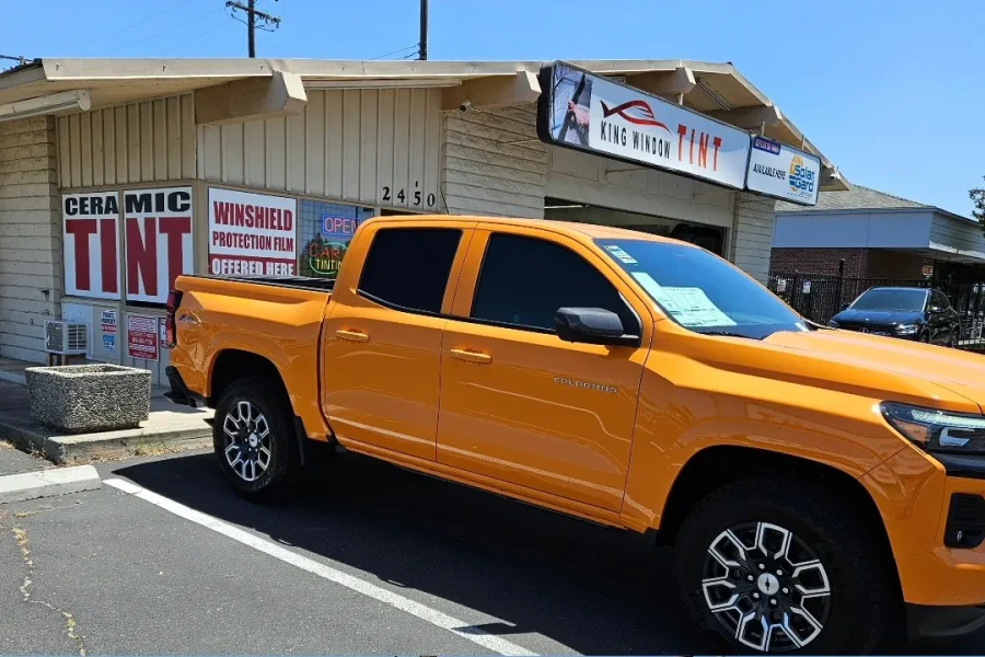 Orange Chevrolet Colorado with freshly tinted windows, in the King Window Tint parking lot on Fulton Avenue, Sacramento