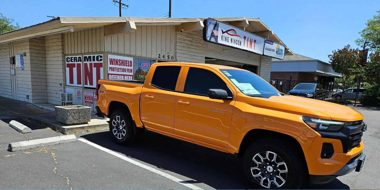 Orange Chevrolet Colorado with freshly tinted windows, in the King Window Tint parking lot on Fulton Avenue, Sacramento