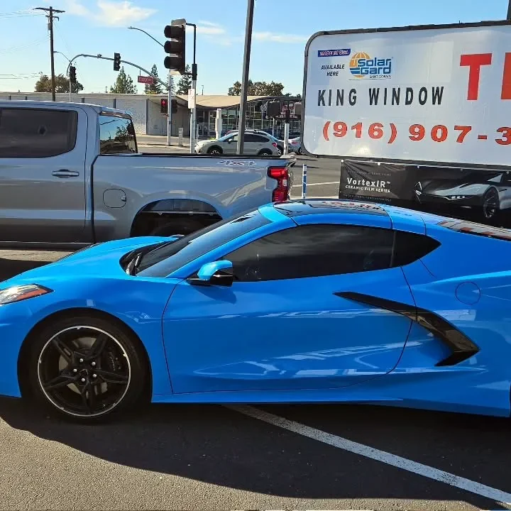 Rapid Blue Chevrolet Corvette Stingray with freshly tinted windows, beside the King Window Tint sign on Fulton Ave, Sacramento