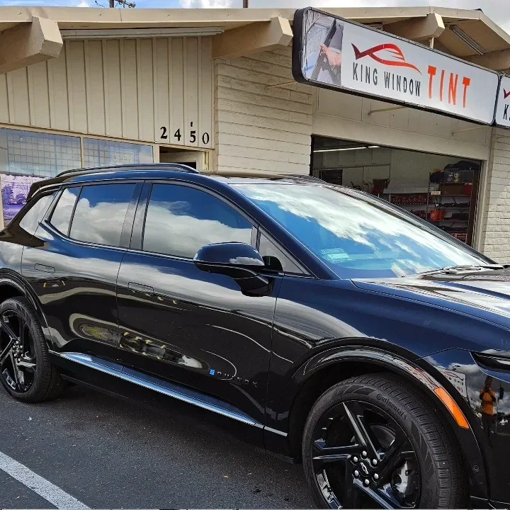 Black Chevrolet Equinox EV with freshly tinted windows, beside the King Window Tint sign on Fulton Ave, Sacramento