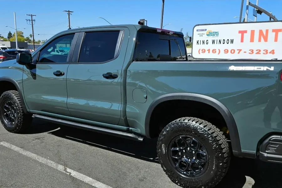 Dark green Chevrolet Silverado ZR2 with freshly tinted windows, beside the King Window Tint sign on Fulton Ave, Sacramento