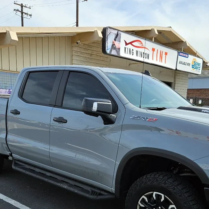 Gray Chevrolet Silverado ZR2 with freshly tinted windows, beside the King Window Tint sign on Fulton Ave, Sacramento