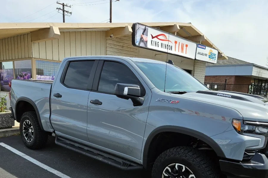 Gray Chevrolet Silverado ZR2 with freshly tinted windows, beside the King Window Tint sign on Fulton Ave, Sacramento