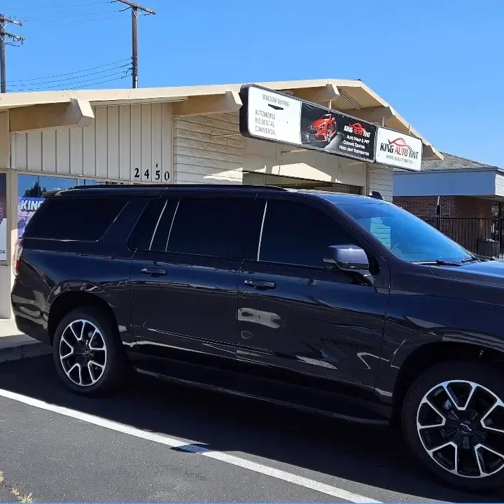 Dark gray Chevrolet Suburban with freshly tinted windows, in the King Auto Tint parking lot on Fulton Avenue, Sacramento