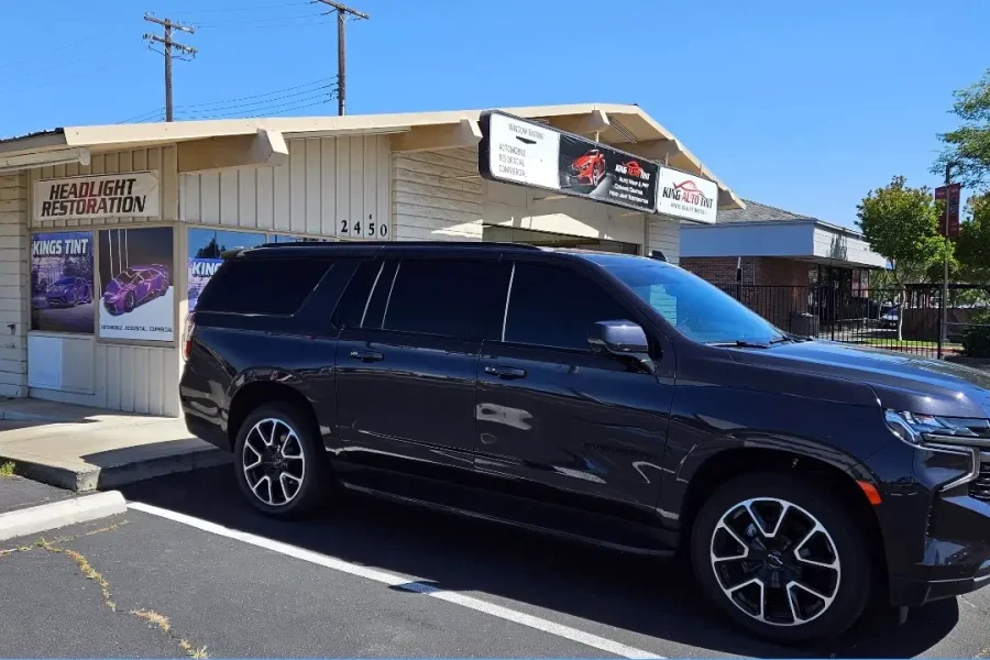 Dark gray Chevrolet Suburban with freshly tinted windows, in the King Auto Tint parking lot on Fulton Avenue, Sacramento