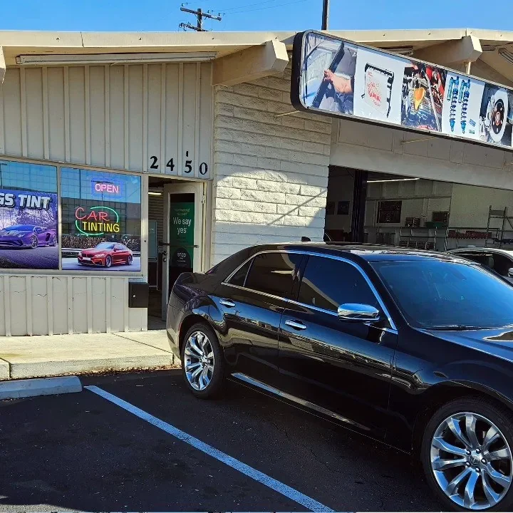 Black Chrysler 300 with freshly tinted windows, beside the King Auto Tint sign on Fulton Ave, Sacramento