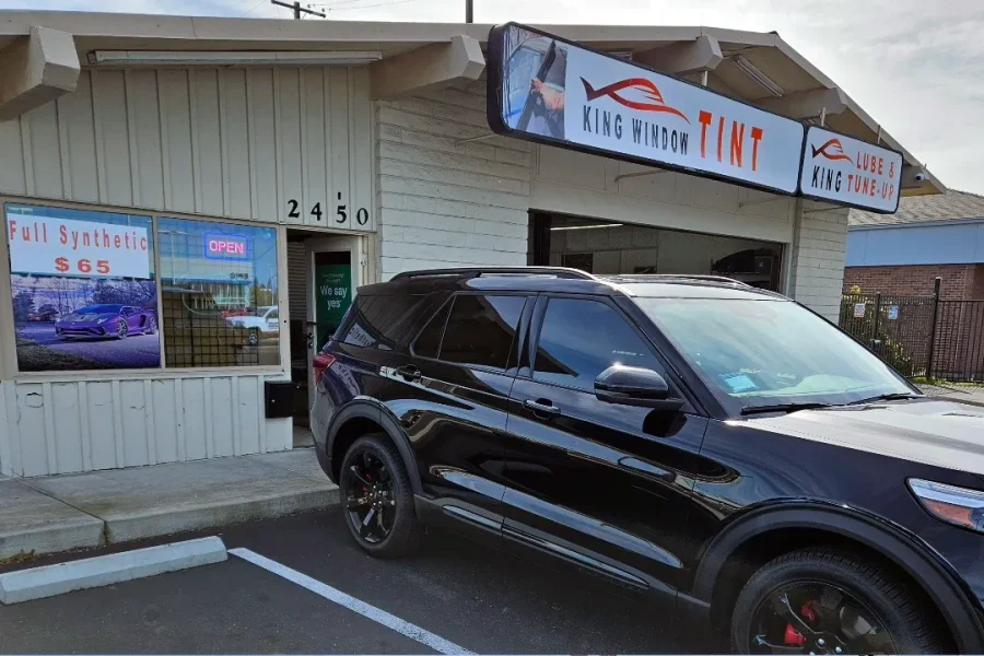 Black Ford Explorer ST with freshly tinted windows, beside the King Window Tint sign on Fulton Ave, Sacramento