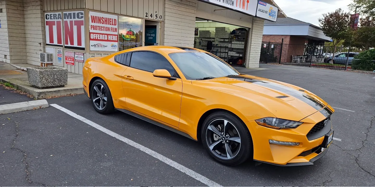 Orange Ford Mustang with freshly tinted windows, outside the King Window Tint shop on Fulton Ave in Sacramento