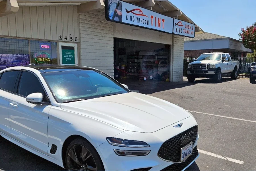 White Genesis G70 with freshly tinted windows, outside the King Window Tint shop on Fulton Ave in Sacramento