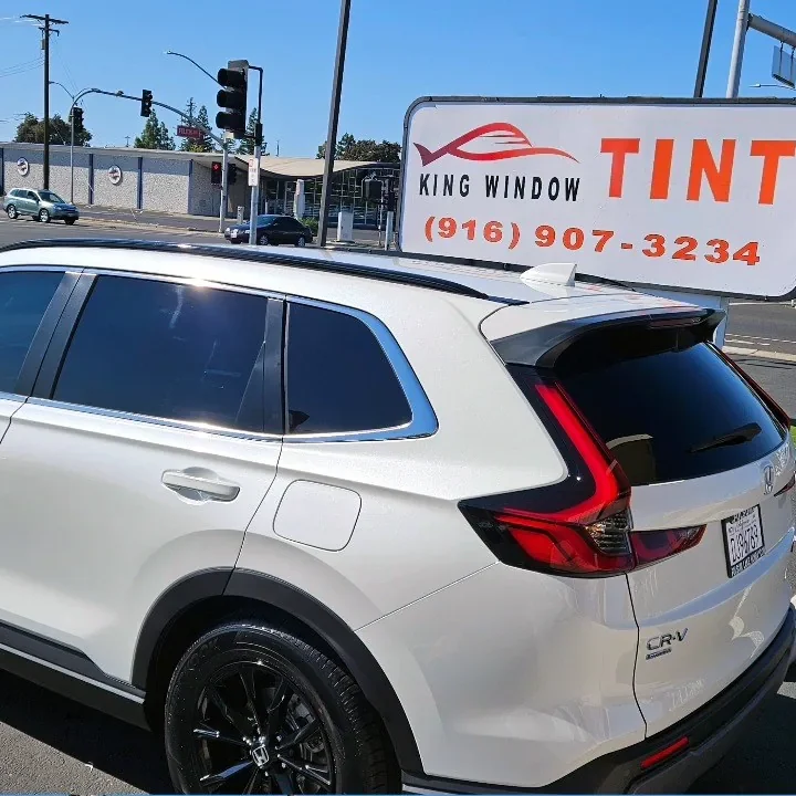 White Honda CR-V with freshly tinted windows, beside the King Window Tint sign on Fulton Ave, Sacramento