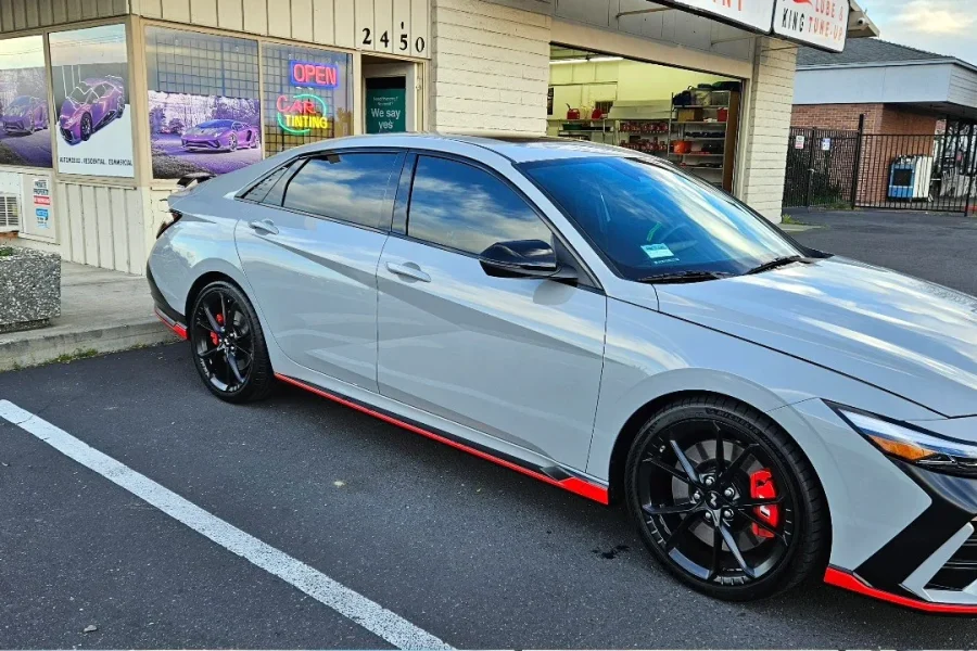 Gray Hyundai Elantra N with freshly tinted windows, beside the King Window Tint sign on Fulton Ave, Sacramento