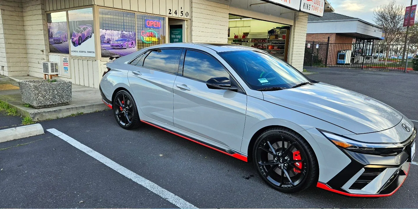 Gray Hyundai Elantra N with freshly tinted windows, beside the King Window Tint sign on Fulton Ave, Sacramento