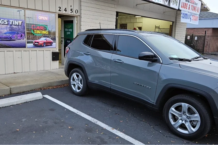 Gray Jeep Compass with freshly tinted windows, outside the King Auto Tint shop on Fulton Ave in Sacramento