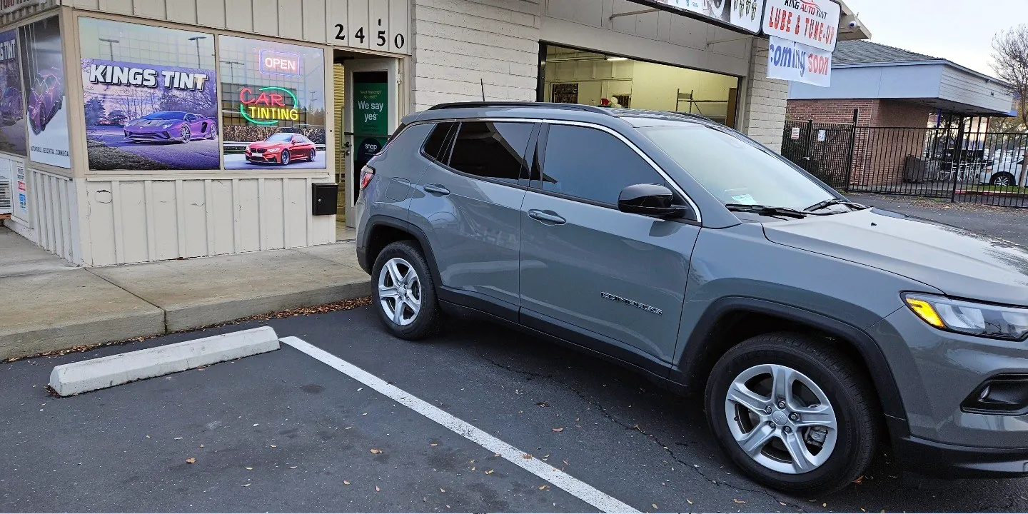 Gray Jeep Compass with freshly tinted windows, outside the King Auto Tint shop on Fulton Ave in Sacramento