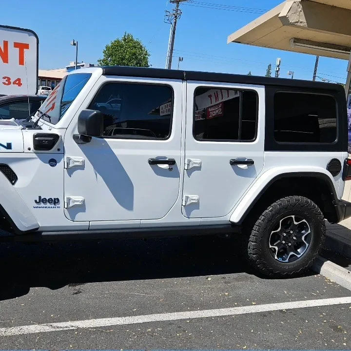 White Jeep Wrangler Rubicon with freshly tinted windows, beside the King Window Tint sign on Fulton Ave, Sacramento