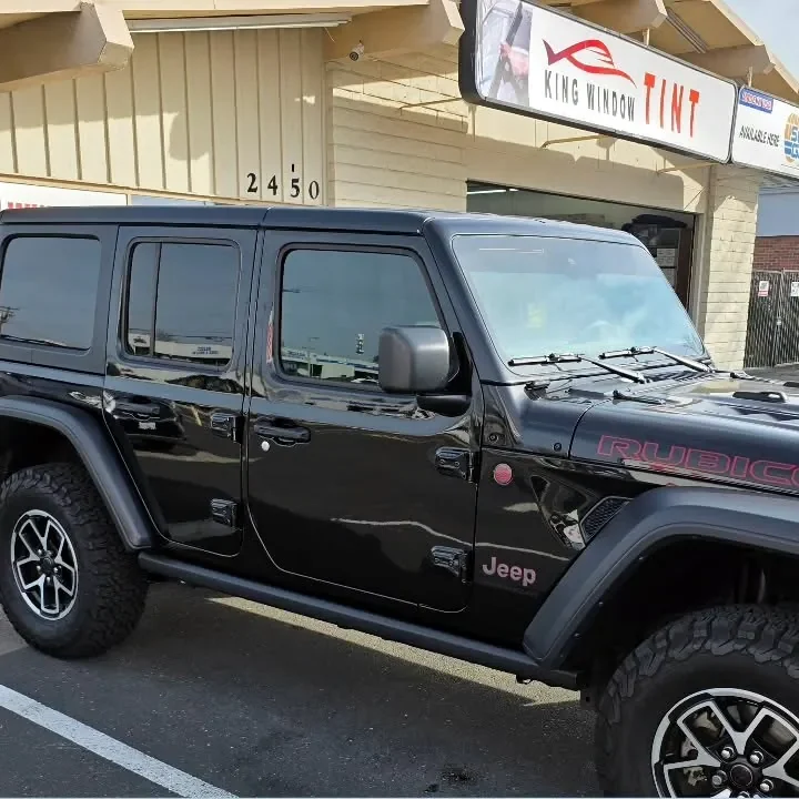 Black Jeep Wrangler Rubicon with freshly tinted windows, beside the King Window Tint sign on Fulton Ave, Sacramento