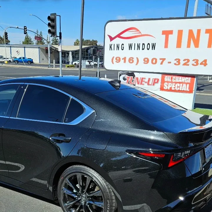 Black Lexus IS 350 with freshly tinted windows, beside the King Window Tint sign on Fulton Ave, Sacramento