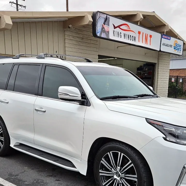 White Lexus LX 570 with freshly tinted windows, beside the King Window Tint sign on Fulton Ave, Sacramento