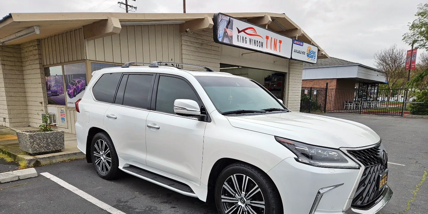 White Lexus LX 570 with freshly tinted windows, beside the King Window Tint sign on Fulton Ave, Sacramento