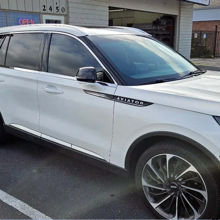 White Lincoln Aviator with freshly tinted windows, beside the King Window Tint sign on Fulton Ave, Sacramento