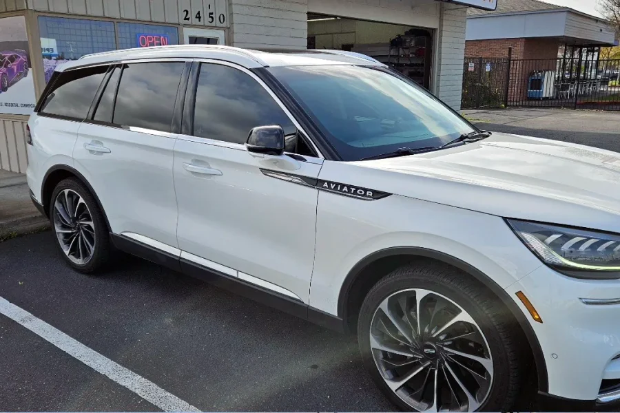 White Lincoln Aviator with freshly tinted windows, beside the King Window Tint sign on Fulton Ave, Sacramento