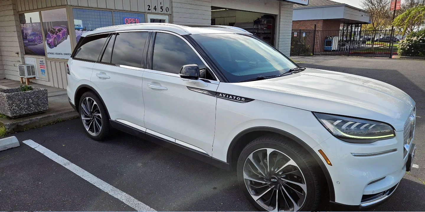White Lincoln Aviator with freshly tinted windows, beside the King Window Tint sign on Fulton Ave, Sacramento