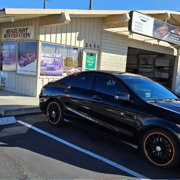 Black Mercedes-Benz CLA 250 with freshly tinted windows, outside the King Auto Tint shop on Fulton Ave in Sacramento (orange-accented wheels)
