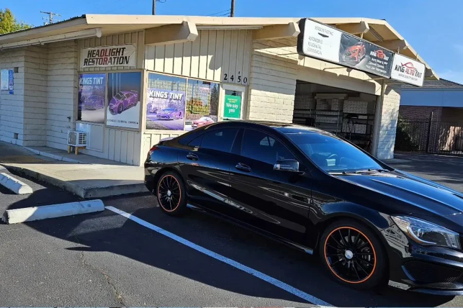 Black Mercedes-Benz CLA 250 with freshly tinted windows, outside the King Auto Tint shop on Fulton Ave in Sacramento (orange-accented wheels)