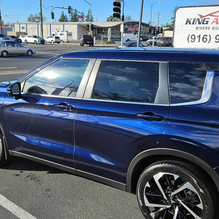 Blue Mitsubishi Outlander with freshly tinted windows, beside the King Window Tint sign on Fulton Ave, Sacramento