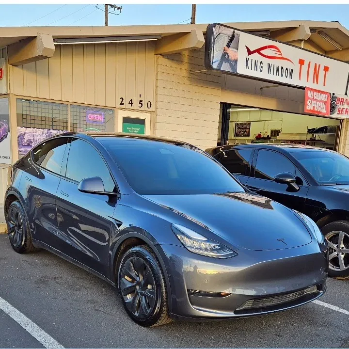 Black Porsche Macan with freshly tinted windows, outside the King Window Tint shop on Fulton Ave in Sacramento (shown with a gray Tesla Model Y)