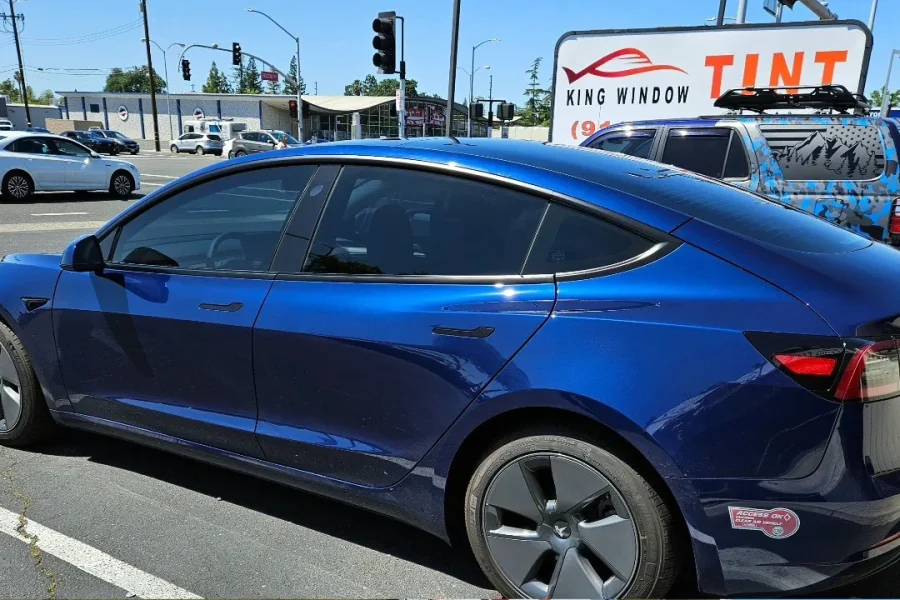 Blue Tesla Model 3 with freshly tinted windows, in the King Window Tint parking lot on Fulton Avenue, Sacramento