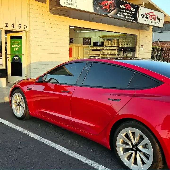 Red Tesla Model 3 with freshly tinted windows, outside the King Auto Tint shop on Fulton Ave in Sacramento