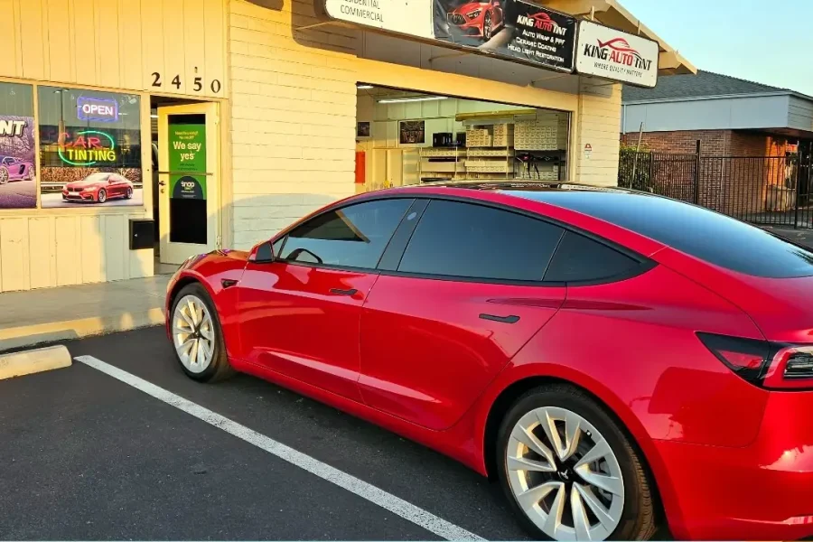 Red Tesla Model 3 with freshly tinted windows, outside the King Auto Tint shop on Fulton Ave in Sacramento
